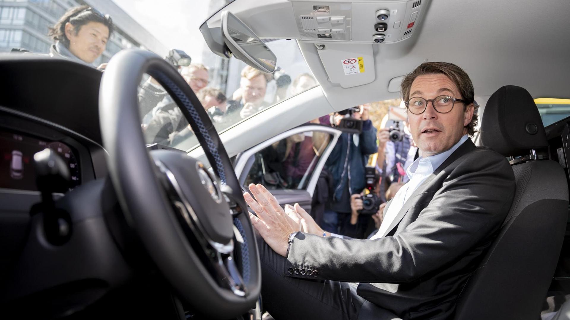 Andreas Scheuer (CSU), Bundesverkehrsminister, sitzt bei einer Veranstaltung zur Eröffnung eines Testfelds für automatisiertes und vernetztes Fahren in Berlin auf dem Beifahrersitz in einem automatisierten Fahrzeug. Auf dem Fahrersitz sitzt niemand, Scheuer greift in die Luft, als fasse er ein Lenkrad an. Andreas Scheuer (CSU), Bundesverkehrsminister, sitzt bei einer Veranstaltung zur Eröffnung eines Testfelds für automatisiertes und vernetztes Fahren in Berlin auf dem Beifahrersitz in einem automatisierten Fahrzeug. Auf dem Fahrersitz sitzt niemand, Scheuer greift in die Luft, als fasse er ein Lenkrad an.