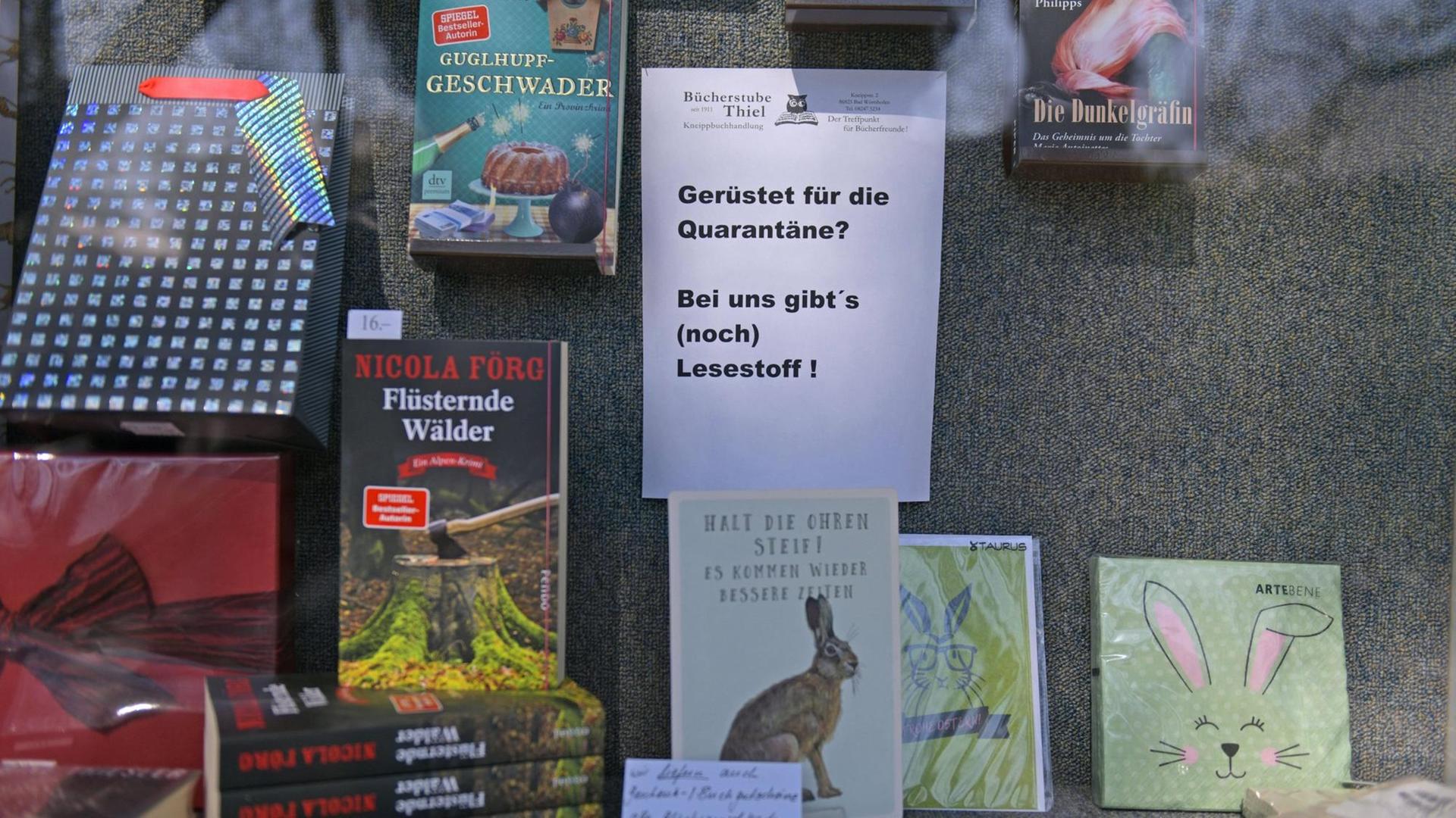 Ausschnitt eines Schaufensters einer Buchhandlung in Bayern: Zu sehen sind verschiedene Bücher, dazwischen ein Schild mit der Aufschrift "Gerüstet für die Quarantäne? Bei uns gibt es (noch) Lesestoff!" Ausschnitt eines Schaufensters einer Buchhandlung in Bayern: Zu sehen sind verschiedene Bücher, dazwischen ein Schild mit der Aufschrift "Gerüstet für die Quarantäne? Bei uns gibt es (noch) Lesestoff!"