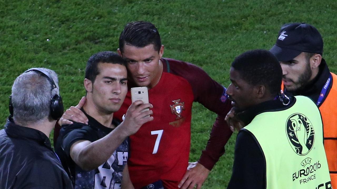 Ein aufs Feld gestürmter Fan macht nach dem EM-Spiel Portugal-Österreich ein Selfie mit Cristiano Ronaldo, bevor ihn die Ordner wegführen. Ein aufs Feld gestürmter Fan macht nach dem EM-Spiel Portugal-Österreich ein Selfie mit Cristiano Ronaldo, bevor ihn die Ordner wegführen.