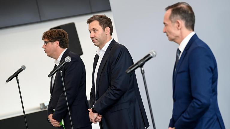 Michael Kellner, Lars Klingbeil und Volker Wissing stehen gemeinsam vor Mikrofonen . Vor der Seite fotografiert blicken sie in die Richtung der Pressevertreter.
