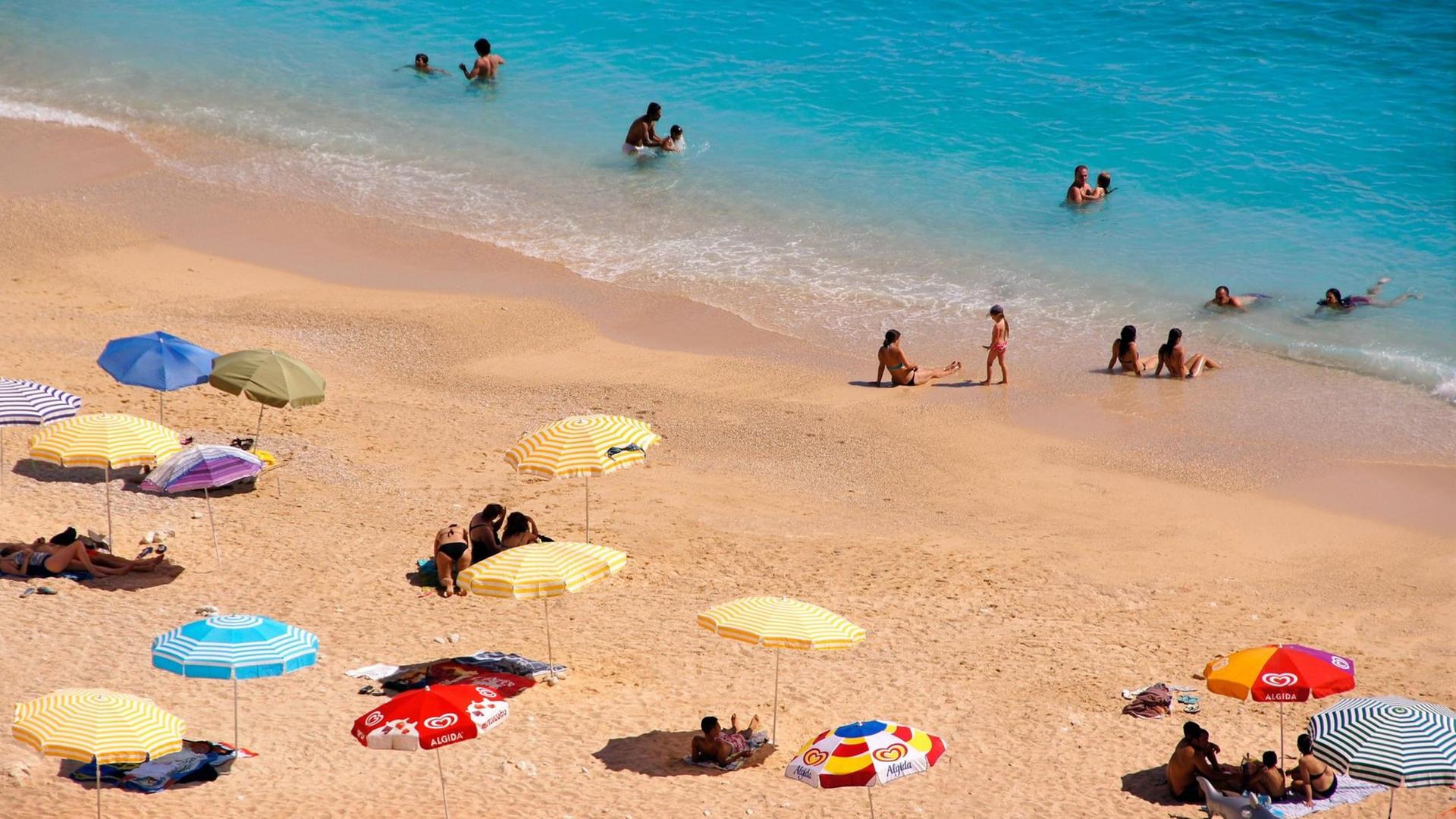 Sonnenschirme und Menschen am Strand in der Nähre von Kas in der Türkei Sonnenschirme und Menschen am Strand in der Nähre von Kas in der Türkei