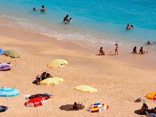 Sonnenschirme und Menschen am Strand in der Nähre von Kas in der Türkei
