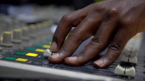 Hand eines Tontechnikers am Mischpult in der im Land sehr beliebten Radiostation Radio Isanganiro von Burundi