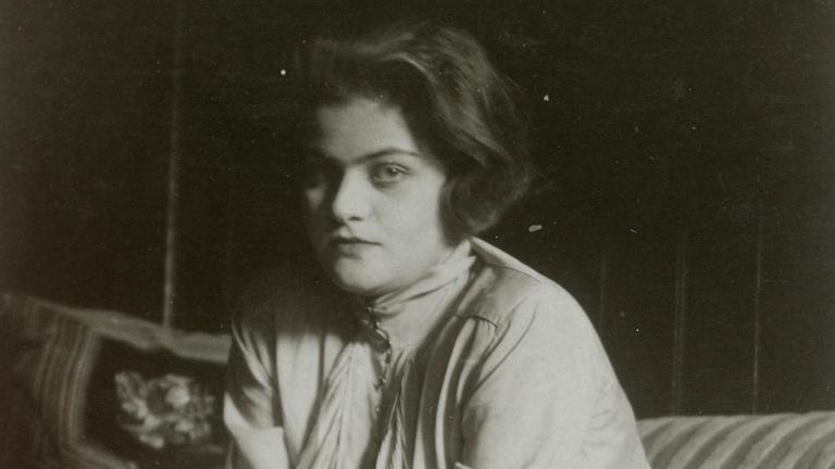 Das Foto zeigt die Bildhauerin Anna Mahler (1904 - 1988), die auf einem Sofa sitzt.