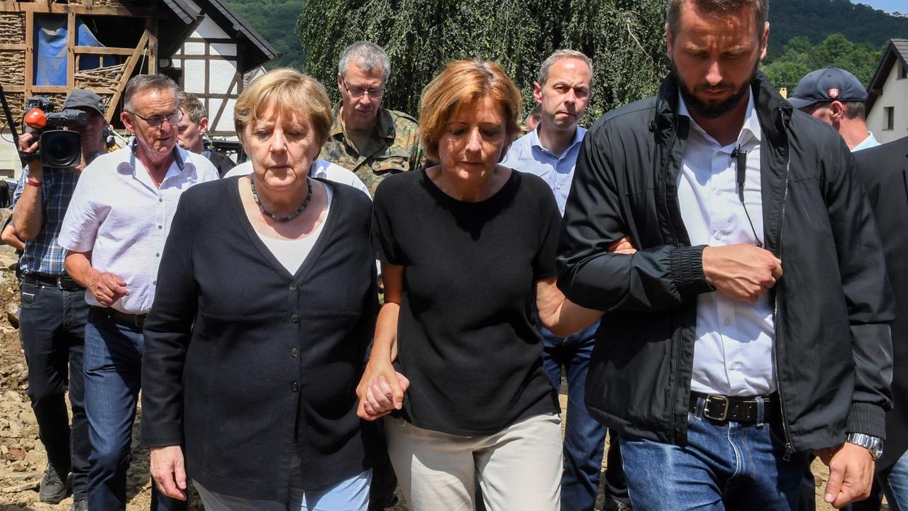 Bundeskanzlerin Angela Merkel (l) und Malu Dreyer (M,SPD), Ministerpräsidentin von Rheinland-Pfalz, gehen durch das vom Hochwasser verwüstete Dorf Schuld in der Nähe von Bad Neuenahr-Ahrweiler.