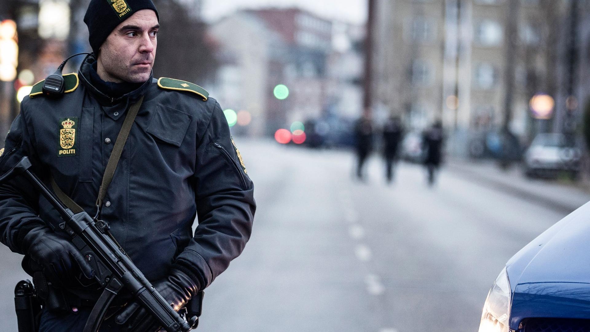 Ein bewaffneter Polizeibeamter steht neben einem Polizeifahrzeug. Ein bewaffneter Polizeibeamter steht neben einem Polizeifahrzeug.