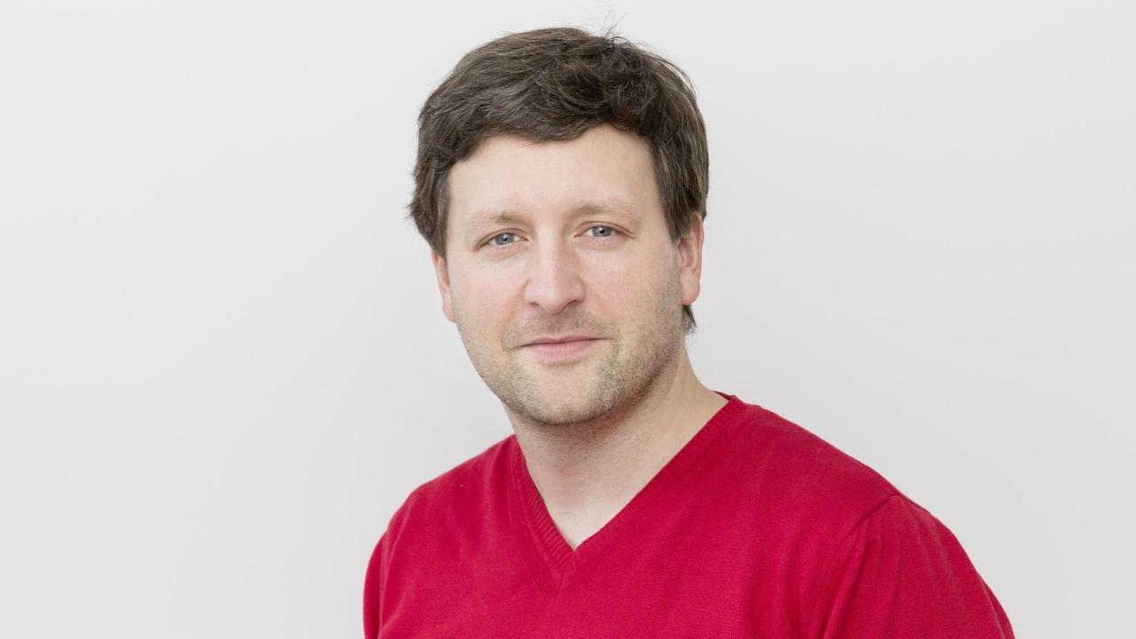 Der Philosoph Christian Neuhäuser trägt roten Pulli und schaut in die Kamera. Der Philosoph Christian Neuhäuser trägt roten Pulli und schaut in die Kamera.