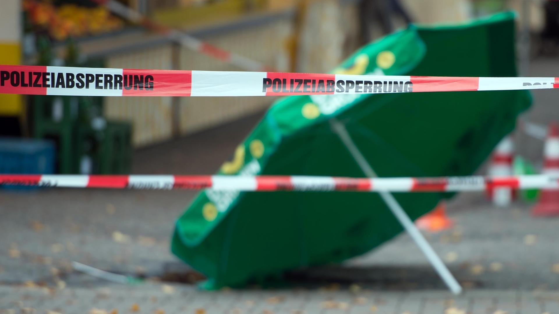 Hinter Polizei-Absperrbändern liegt an einen Tatort ein Wahlkampfschirm der Grünen. Hinter Polizei-Absperrbändern liegt an einen Tatort ein Wahlkampfschirm der Grünen.