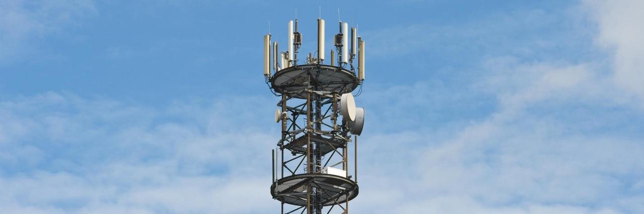 Ein Mobilfunkmast ist vor weiß-blauem Himmel zu sehen. Ein Mobilfunkmast ist vor weiß-blauem Himmel zu sehen.