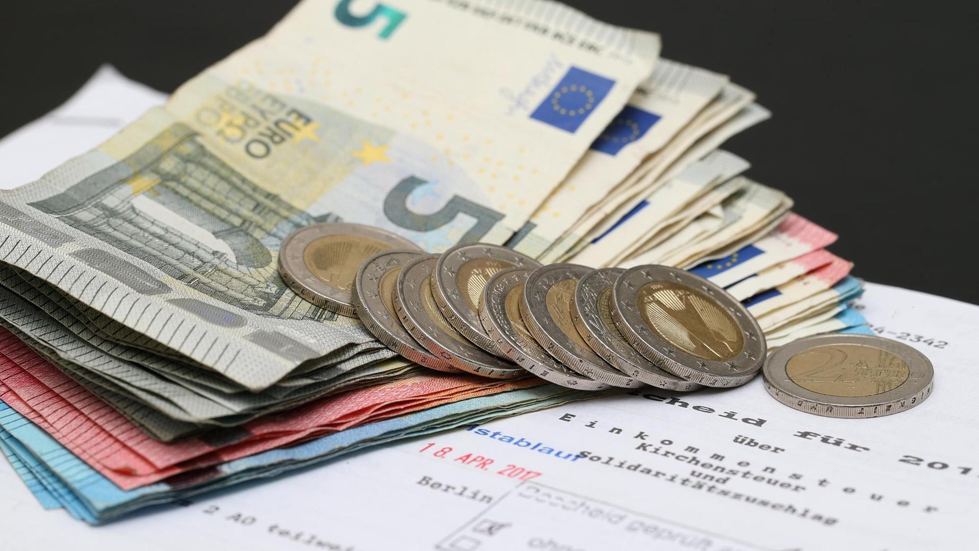 Symbolbild Steuererklärung, Steuerbescheid mit Euro-Münzen und -Scheinen Symbolbild Steuererklärung, Steuerbescheid mit Euro-Münzen und -Scheinen