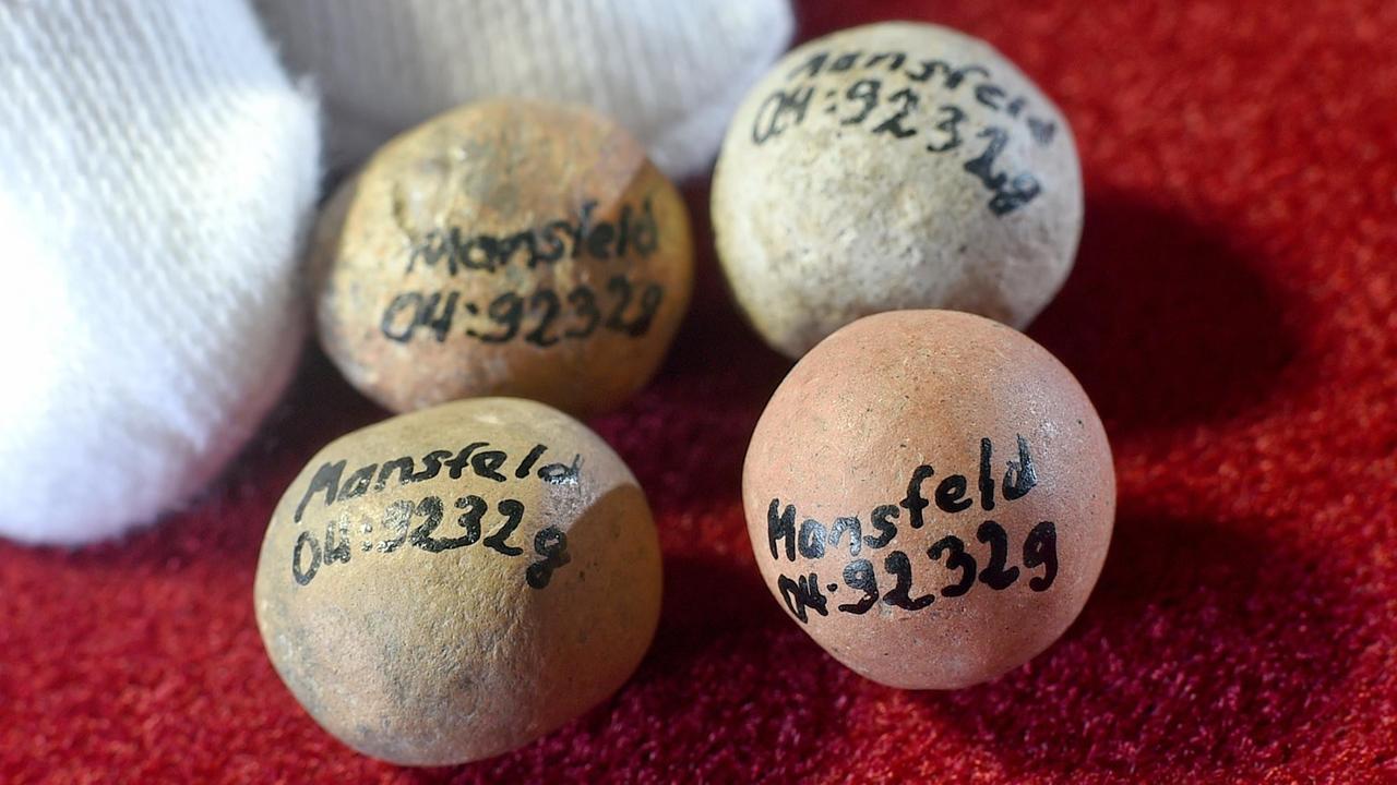 Vier Murmeln aus Stein liegen auf rotem Hintergrund. Vier Murmeln aus Stein liegen auf rotem Hintergrund.