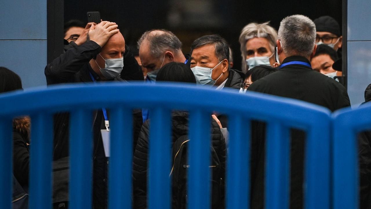Die Mitglieder der Delegation stehen hinter einem leuchtend blauen Zaun. Die Mitglieder der Delegation stehen hinter einem leuchtend blauen Zaun.