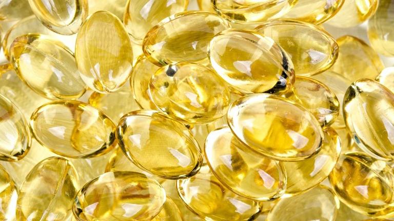 Kleine gold-gelbe Kapslen mit Flüssigkeit befüllt Kleine gold-gelbe Kapslen mit Flüssigkeit befüllt