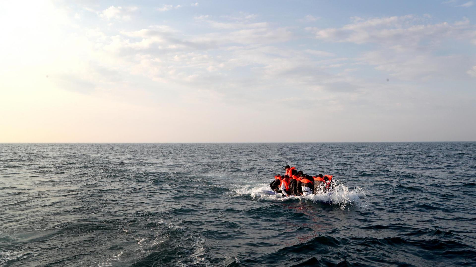 Eine Gruppe von Migranten überquert den Ärmel-Kanal in einem kleinen Boot. Eine Gruppe von Migranten überquert den Ärmel-Kanal in einem kleinen Boot.
