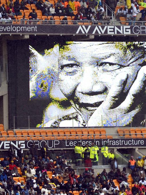 Im mit Menschen gefüllten Fußballstadion von Johannesburg hängt ein Mandela-Plakat
