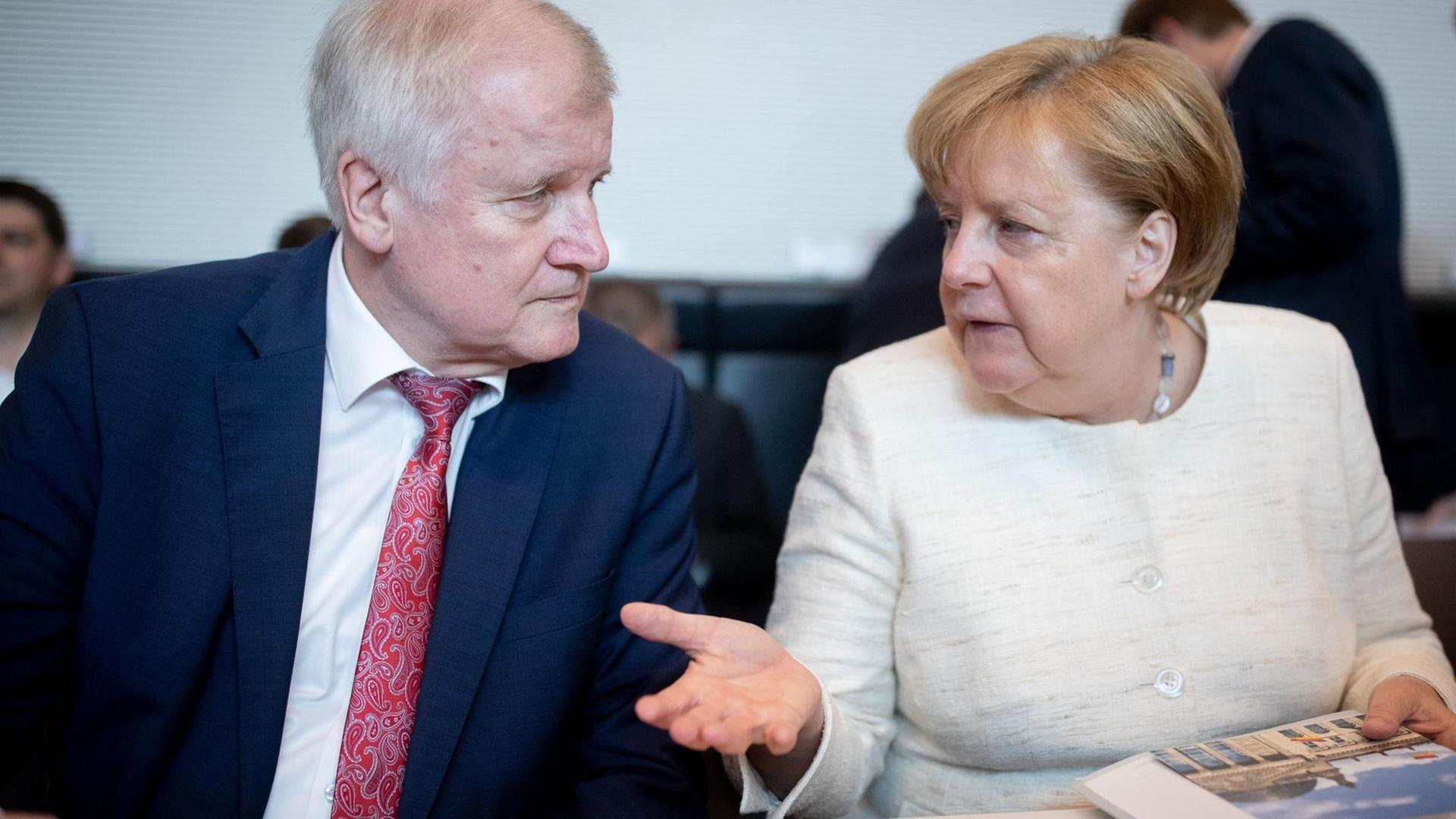 12.06.2018, Berlin: Bundeskanzlerin Angela Merkel (CDU) und Horst Seehofer (CSU), Bundesminister für Inneres, Heimat und Bau unterhalten sich Beginn der CDU/CSU-Fraktionssitzung im Bundestag. 12.06.2018, Berlin: Bundeskanzlerin Angela Merkel (CDU) und Horst Seehofer (CSU), Bundesminister für Inneres, Heimat und Bau unterhalten sich Beginn der CDU/CSU-Fraktionssitzung im Bundestag.