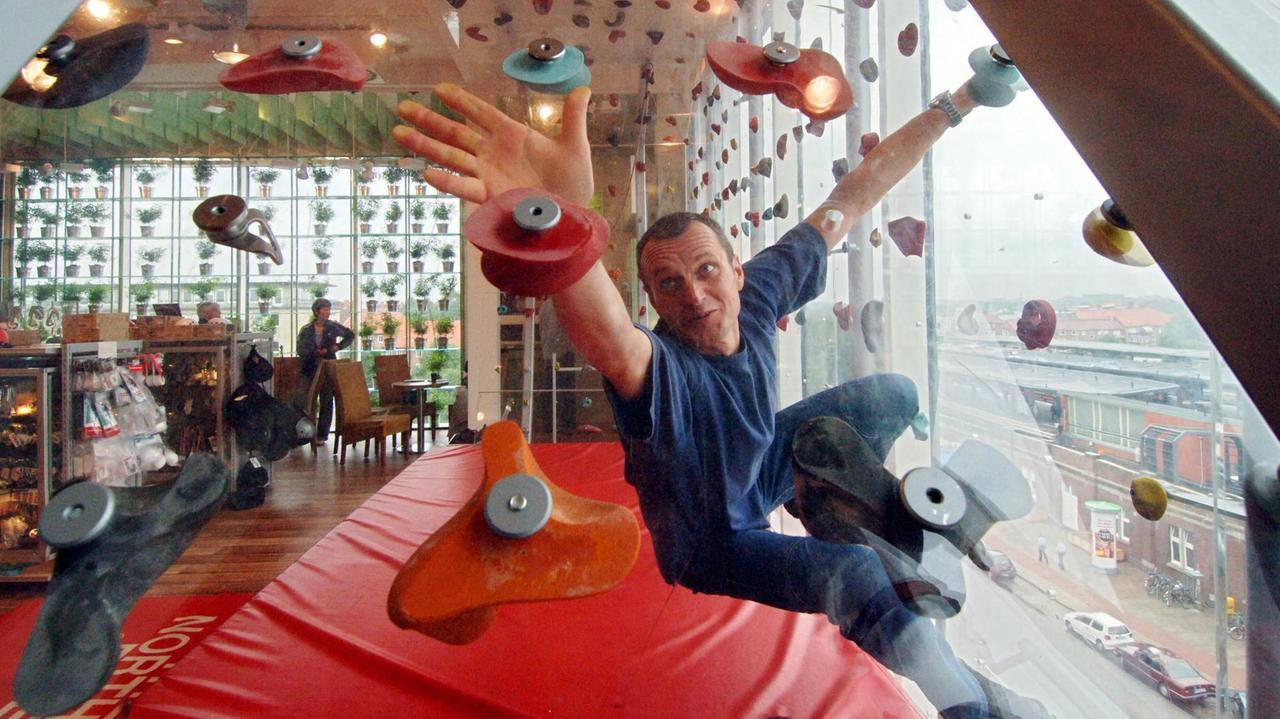 Ein Kunde probiert an der Kletterwand in einem Outdoor-Laden seine neuen Schuhe aus. Ein Kunde probiert an der Kletterwand in einem Outdoor-Laden seine neuen Schuhe aus.