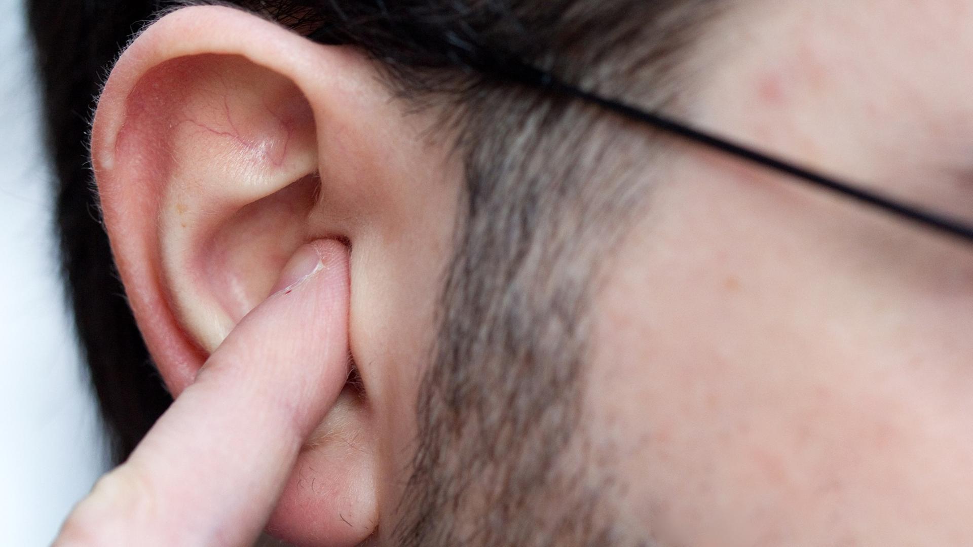 Ein Mann hält sich in Osnabrück als Gehörschutz einen Finger in das Ohr.