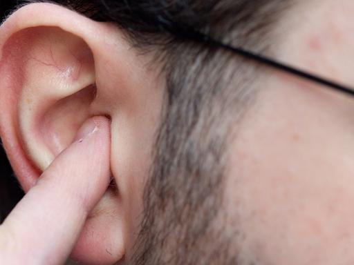 Ein Mann hält sich in Osnabrück als Gehörschutz einen Finger in das Ohr.