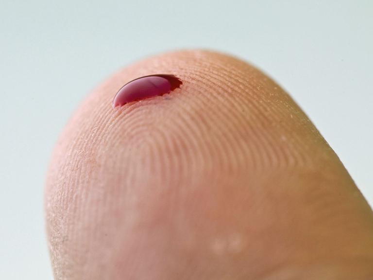 Ein kleiner Blutstropfen auf einem Finger. Mithilfe eines solchen Tropfens und eines Messgerätes können zum Beispiel an Diabetes erkrankte Menschen den Zuckergehalt des Blutes bestimmen.