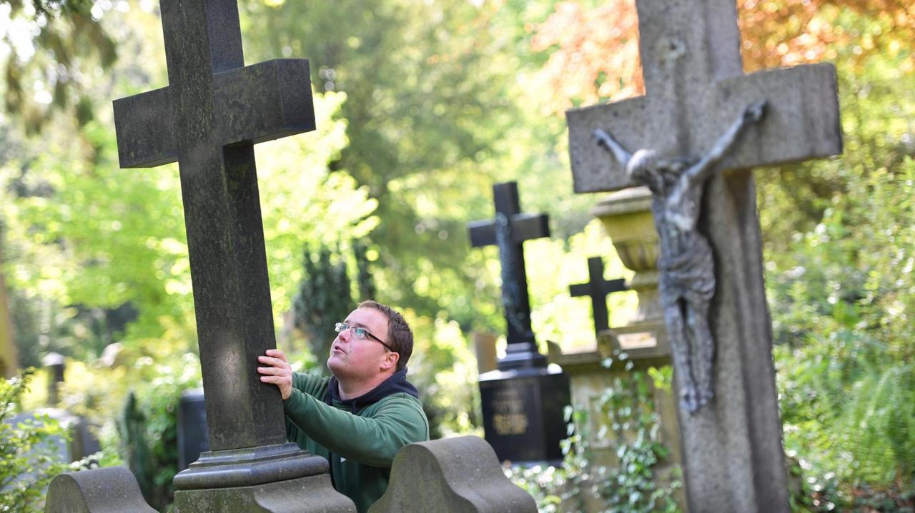 Gärtner Markus Preißler kontrolliert auf dem Hauptfriedhof in Frankfurt am Main das Kreuz eines Grabsteins. Mehrere zehntausend Grabsteine werden jährlich auf ihre Standsicherheit überprüft, um Unfälle zu vermeiden.