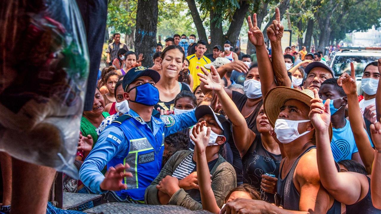 Menschen in San Pedro, Honduras, die für Essen einer Hilfsorganisation anstehen. Sie stehen mit Gesichtsmasken dicht gedrängt vor einem Lkw und strecken die Arme aus. 17.04.2020 Menschen in San Pedro, Honduras, die für Essen einer Hilfsorganisation anstehen. Sie stehen mit Gesichtsmasken dicht gedrängt vor einem Lkw und strecken die Arme aus. 17.04.2020
