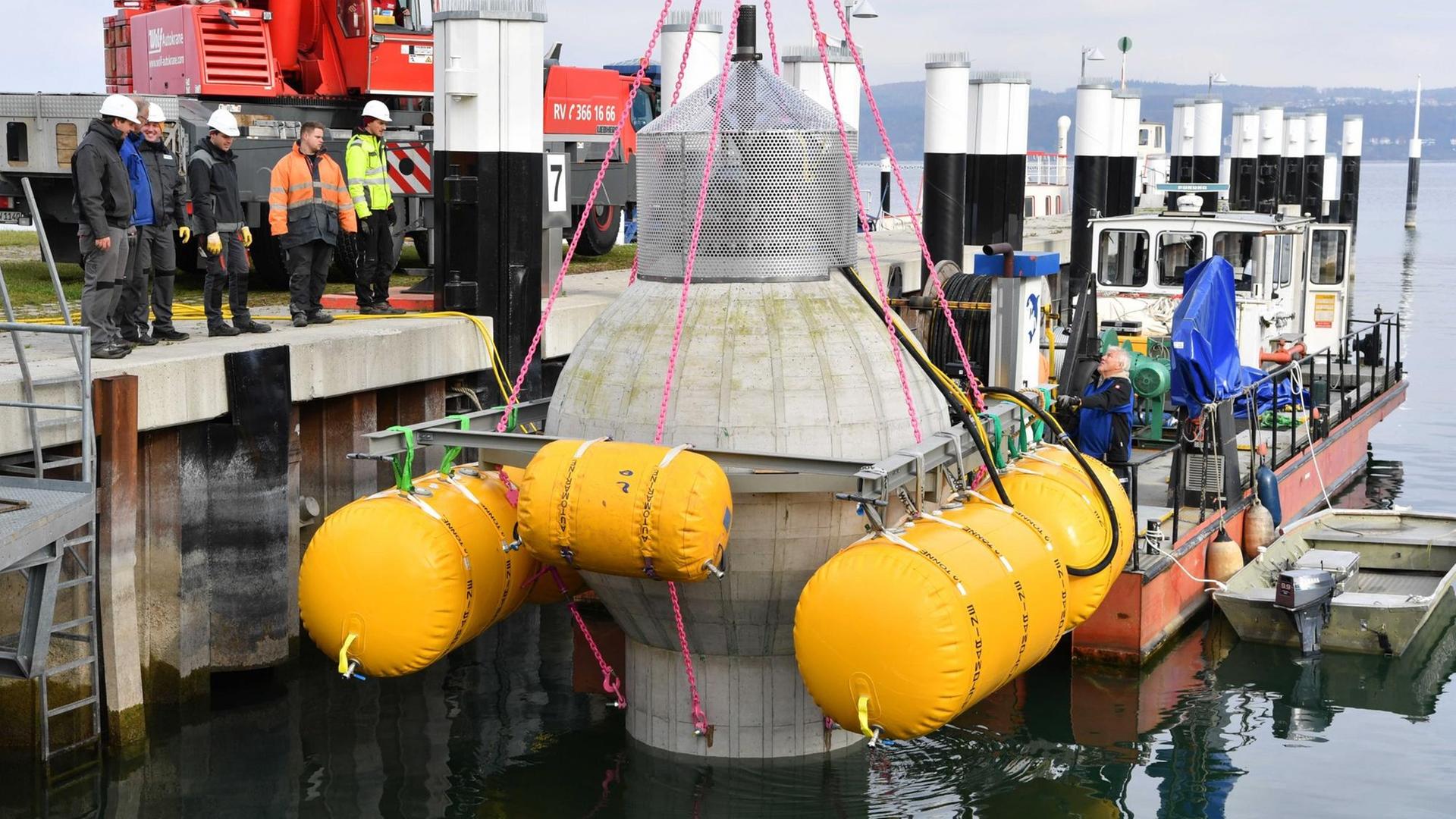 Ein Kran hievt am 08.11.2016 in Konstanz (Baden-Württemberg) einen Kugelpumpspeicher aus Beton ins Hafenbecken, um diesen zu Testzwecken für wenige Wochen im Bodensee zu versenken. Mit der Kugel, die einen Durchmesser von drei Metern hat, soll nach Institutsangaben getestet werden, ob sie unter Wasser als Energiespeicher dienen kann. Ein Kran hievt am 08.11.2016 in Konstanz (Baden-Württemberg) einen Kugelpumpspeicher aus Beton ins Hafenbecken, um diesen zu Testzwecken für wenige Wochen im Bodensee zu versenken. Mit der Kugel, die einen Durchmesser von drei Metern hat, soll nach Institutsangaben getestet werden, ob sie unter Wasser als Energiespeicher dienen kann.