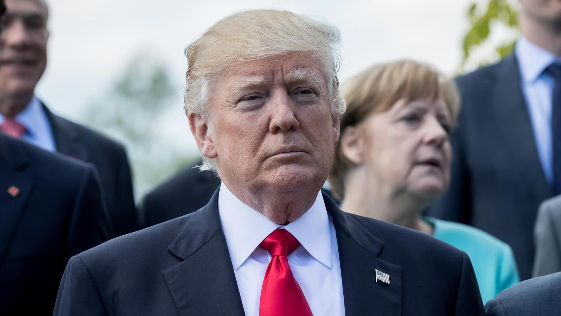 US-Präsident Donald Trump steht vor Bundeskanzlerin Angela Merkel (CDU) am 27.05.2017 beim Familienfoto der G7 Staaten mit den Outreach-Partnern in Taormina auf Sizilien (Italien). US-Präsident Donald Trump steht vor Bundeskanzlerin Angela Merkel (CDU) am 27.05.2017 beim Familienfoto der G7 Staaten mit den Outreach-Partnern in Taormina auf Sizilien (Italien).