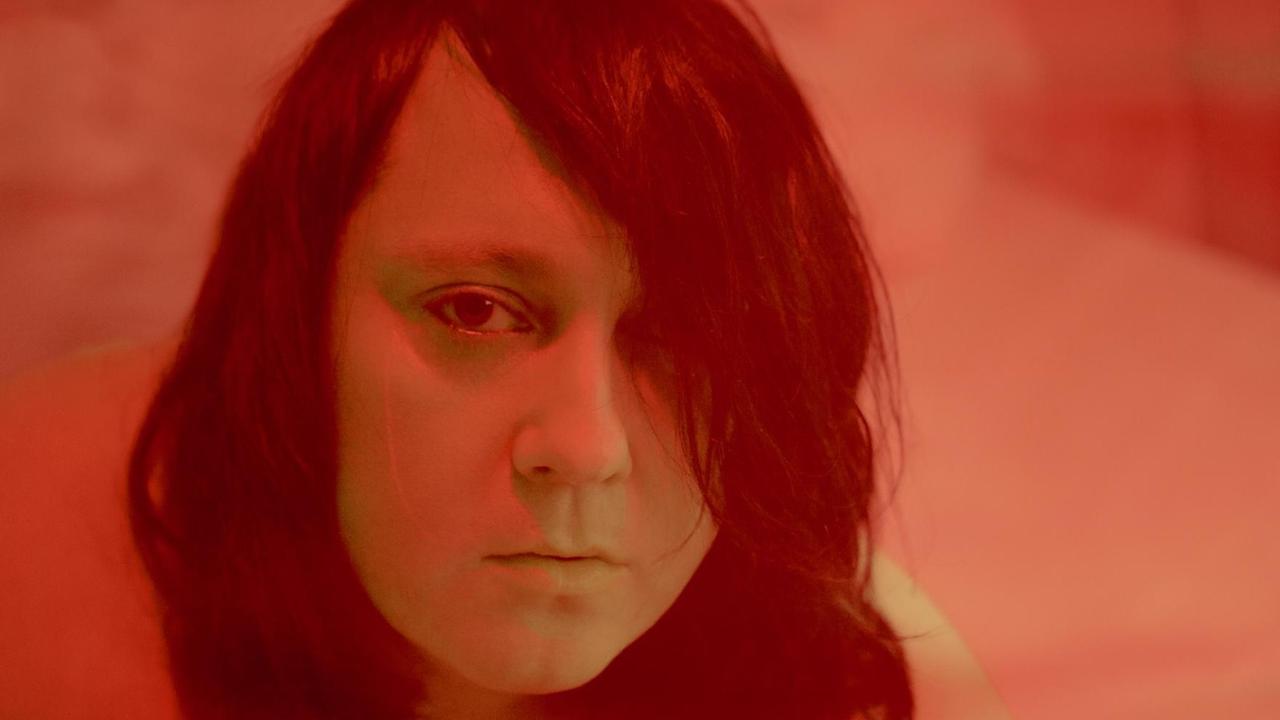 In rotes Licht getauchte Nahaufnahme der Künstlerin Anohni In rotes Licht getauchte Nahaufnahme der Künstlerin Anohni