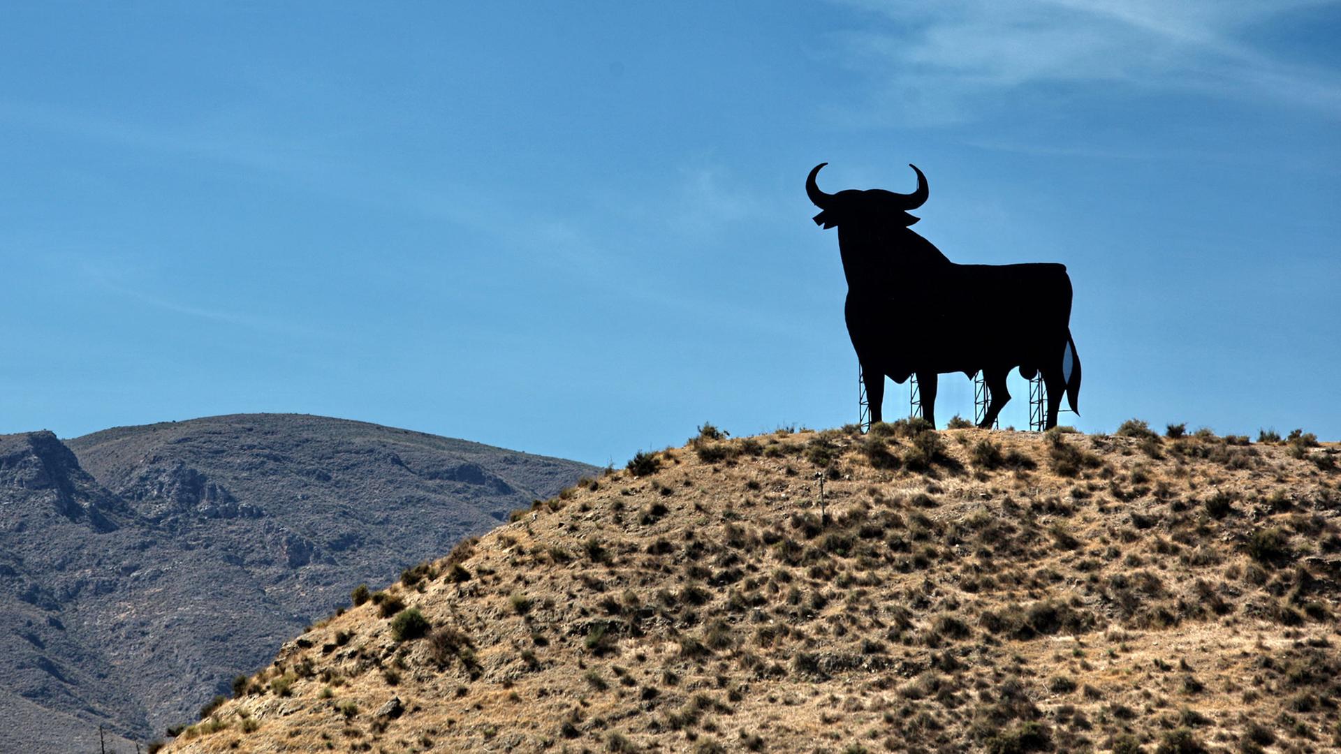 Ein Osborne-Stier, das Markenzeichen von Andalusien und ganz Spanien, steht auf einem Hügel bei Almeria in Andalusien Ein Osborne-Stier, das Markenzeichen von Andalusien und ganz Spanien, steht auf einem Hügel bei Almeria in Andalusien