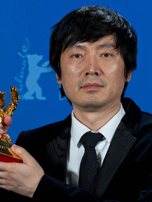 Diao Yinan, der Regisseur des Siegerfilms "Bai Ri Yan Huo (Schwarze Kohle, dünnes Eis)", posiert während der 64. Internationalen Filmfestspiele in Berlin mit dem Goldenen Bären.