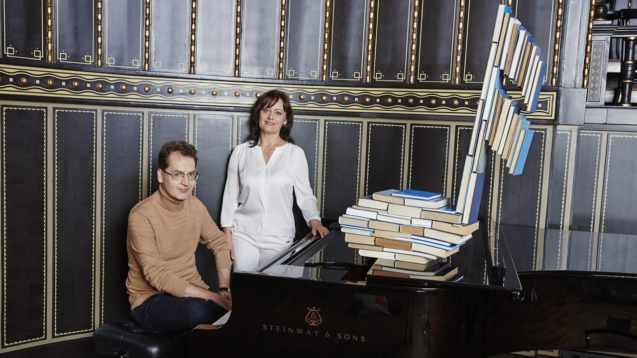 Izabella Simon und Dénes Várjon posieren an einem Flügel vor einer vertäfelten Wand Izabella Simon und Dénes Várjon posieren an einem Flügel vor einer vertäfelten Wand