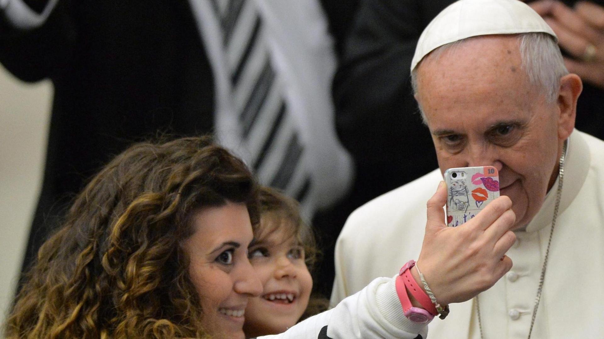 Eine Mutter macht ein Selfie von sich, ihrem Kind und Papst Franziskus während einer Generalaudienz. Eine Mutter macht ein Selfie von sich, ihrem Kind und Papst Franziskus während einer Generalaudienz.