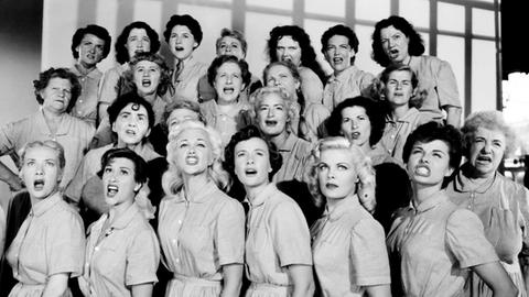 In vier aufsteigenden Reihen stehen die Frauen singend
