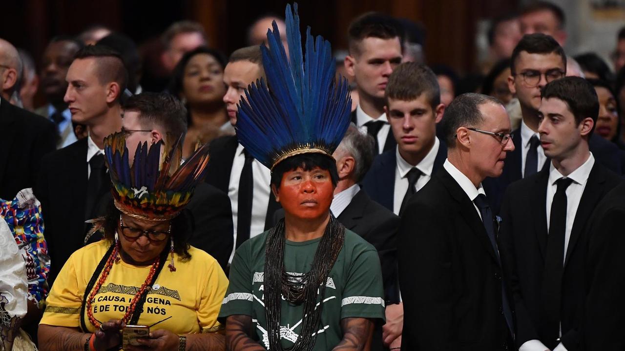 Indigene mit traditionellem Kopfschmuck sind unter den Teilnehmern der Messe. Indigene mit traditionellem Kopfschmuck sind unter den Teilnehmern der Messe.