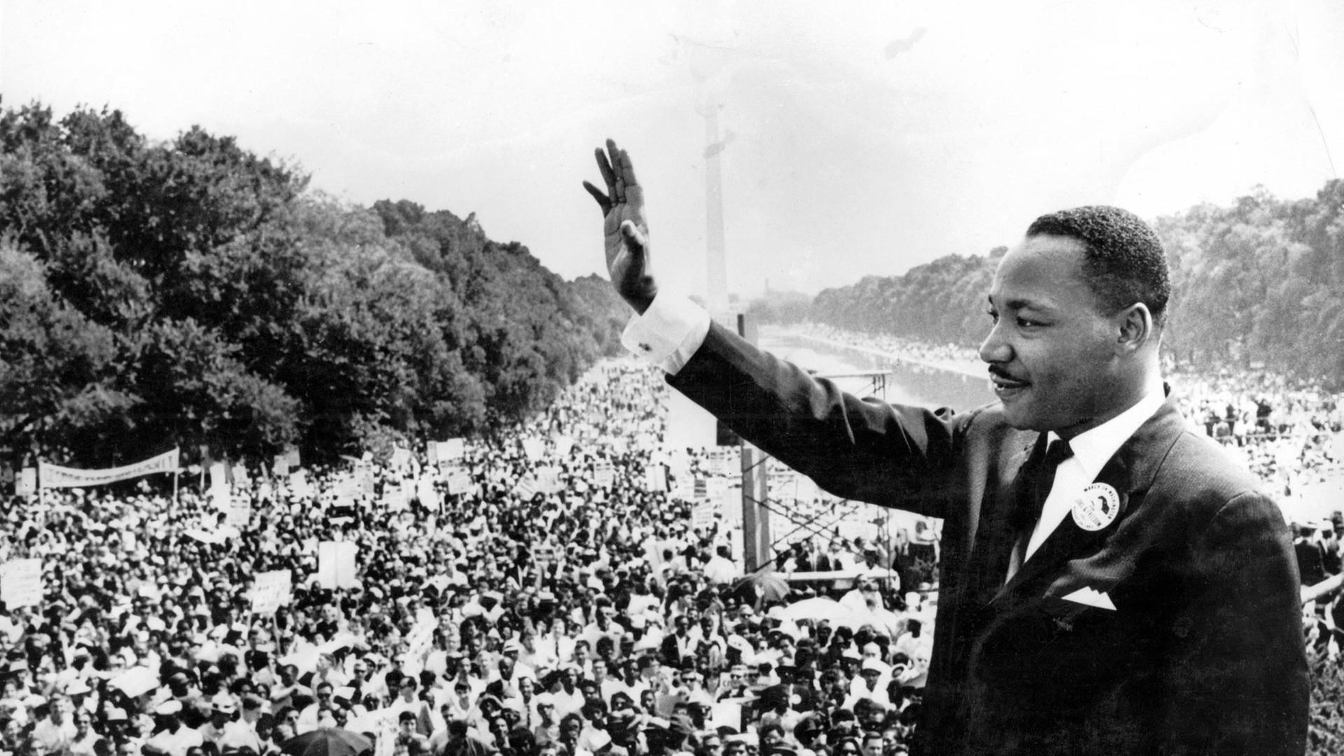 Martin Luther King steht in Washington vor einer Menschenmenge und winkt, im Hintergrund das Lincoln Memorial. Aufnahme vom 30. August 1963. Martin Luther King steht in Washington vor einer Menschenmenge und winkt, im Hintergrund das Lincoln Memorial. Aufnahme vom 30. August 1963.