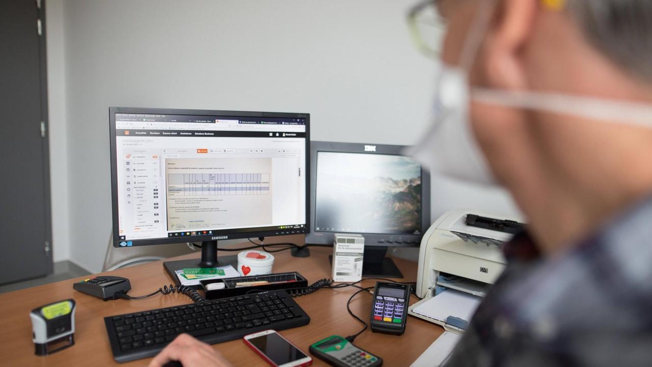 Ain Arzt mit Brille und Schutzmaske sitzt am Computer. Ain Arzt mit Brille und Schutzmaske sitzt am Computer.