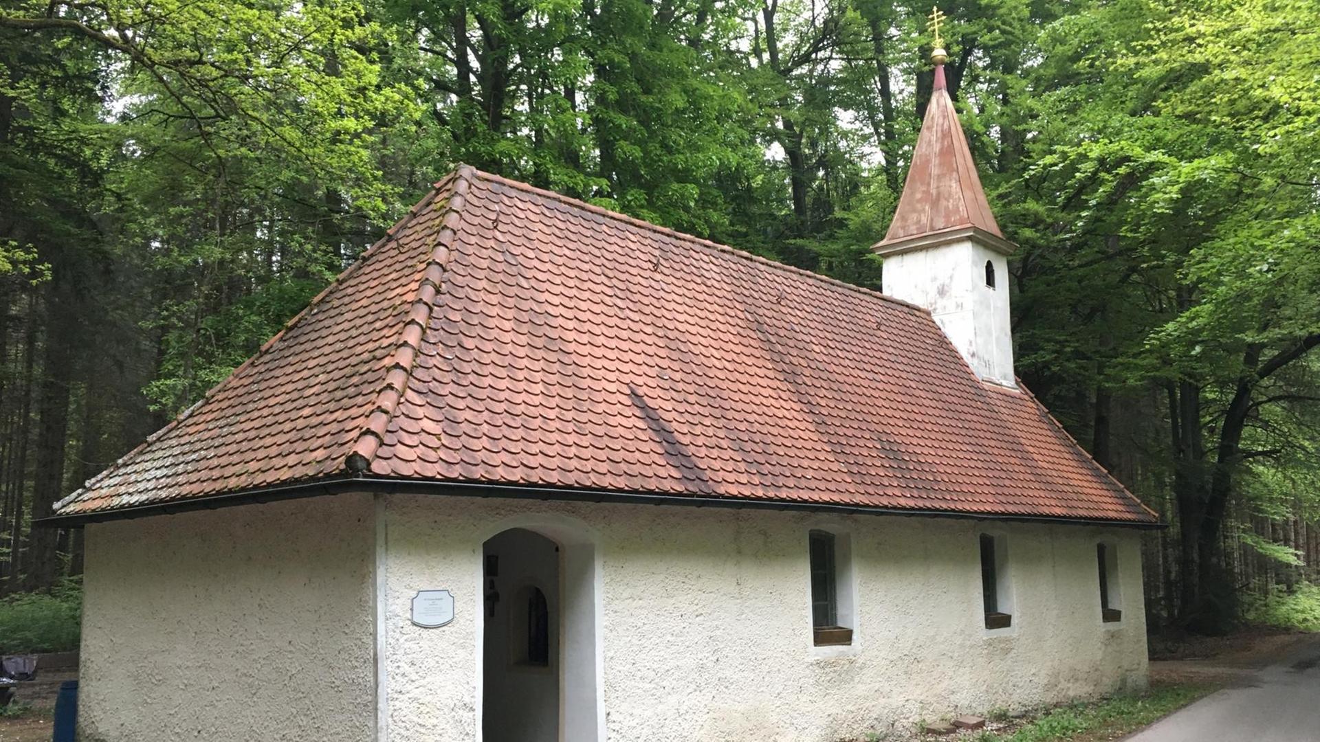 Die St. Corona-Kapelle im bayerischen Sauerlach-Arget: Eine schlichte, weiß verputzte Kapelle mit rotem Ziegeldach und einem kleinen Turm steht im Wald Die St. Corona-Kapelle im bayerischen Sauerlach-Arget: Eine schlichte, weiß verputzte Kapelle mit rotem Ziegeldach und einem kleinen Turm steht im Wald