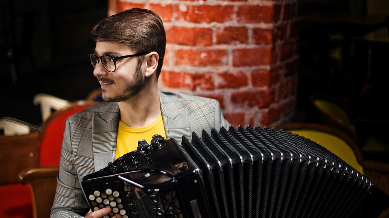 Der Musiker sitzt mit seinem Instrument von einer roten Ziegelwand in einem Konzertraum und spielt Der Musiker sitzt mit seinem Instrument von einer roten Ziegelwand in einem Konzertraum und spielt