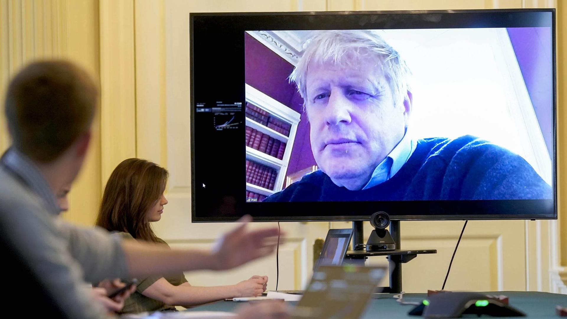 HANDOUT - 28.03.2020, Großbritannien, London: Boris Johnson auf einem Bildschirm während einer Videoschalte aus der häuslichen Quarantäne Foto: Andrew Parsons/10 Downing Street/dpa HANDOUT - 28.03.2020, Großbritannien, London: Boris Johnson auf einem Bildschirm während einer Videoschalte aus der häuslichen Quarantäne Foto: Andrew Parsons/10 Downing Street/dpa