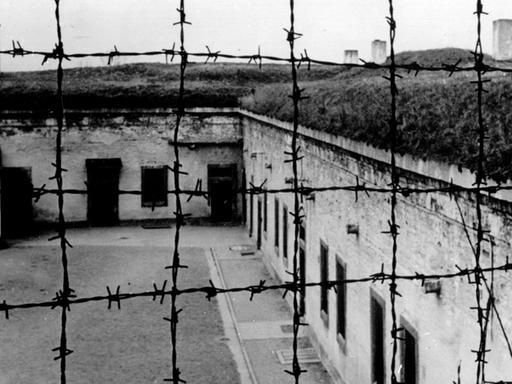 Blick durch Stacheldraht auf die Gebäude des 1941 von der SS errichteten Konzentrationslagers im tschechischen Theresienstadt.