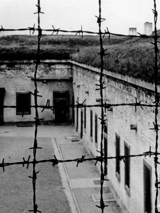 Blick durch Stacheldraht auf die Gebäude des 1941 von der SS errichteten Konzentrationslagers im tschechischen Theresienstadt.