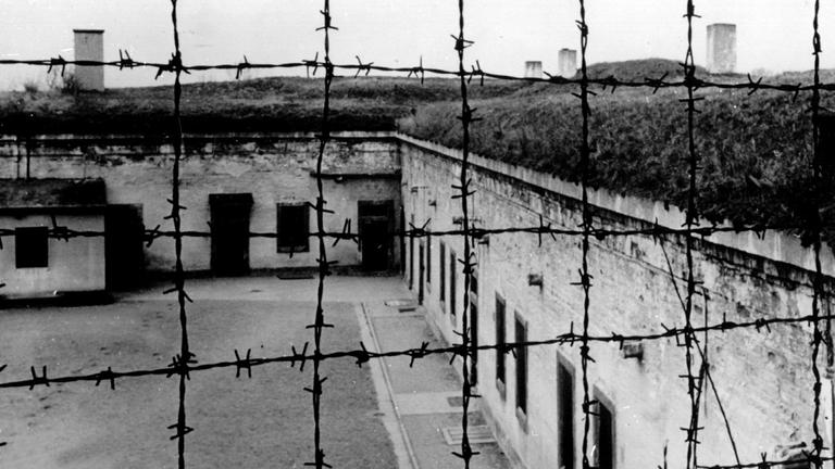 Blick durch Stacheldraht auf die Gebäude des 1941 von der SS errichteten Konzentrationslagers im tschechischen Theresienstadt. Blick durch Stacheldraht auf die Gebäude des 1941 von der SS errichteten Konzentrationslagers im tschechischen Theresienstadt.