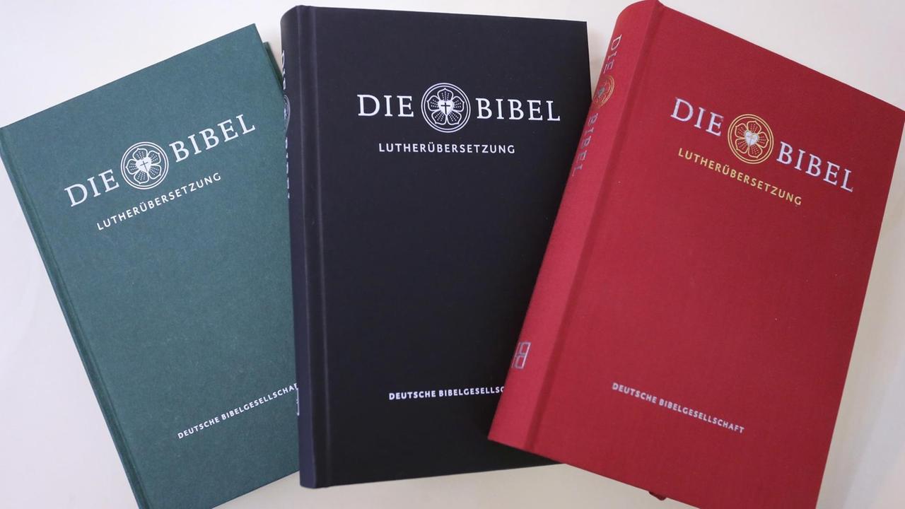 Drei nebeneinander liegende Bibel-Ausgaben in den Farben grün, schwarz und rot. Drei nebeneinander liegende Bibel-Ausgaben in den Farben grün, schwarz und rot.