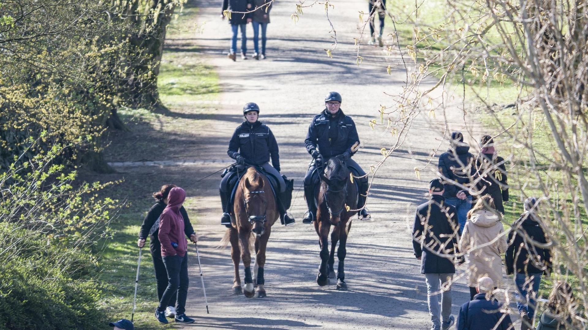 Berittene Polizisten sind am Mainufer unterwegs und achten darauf, dass keine Menschenansammlungen über fünf Personen entstehen, um das Risiko einer Infektion mit dem Coronavirus einzuschränken Berittene Polizisten sind am Mainufer unterwegs und achten darauf, dass keine Menschenansammlungen über fünf Personen entstehen, um das Risiko einer Infektion mit dem Coronavirus einzuschränken