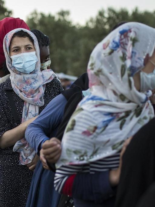 10.09.2020, Griechenland, Moria: Frauen stehen an, um Essen zu erhalten in der Nähe des ausgebrannten Flüchtlingslagers Moria. Mehrere Brände haben das Lager fast vollständig zerstört.