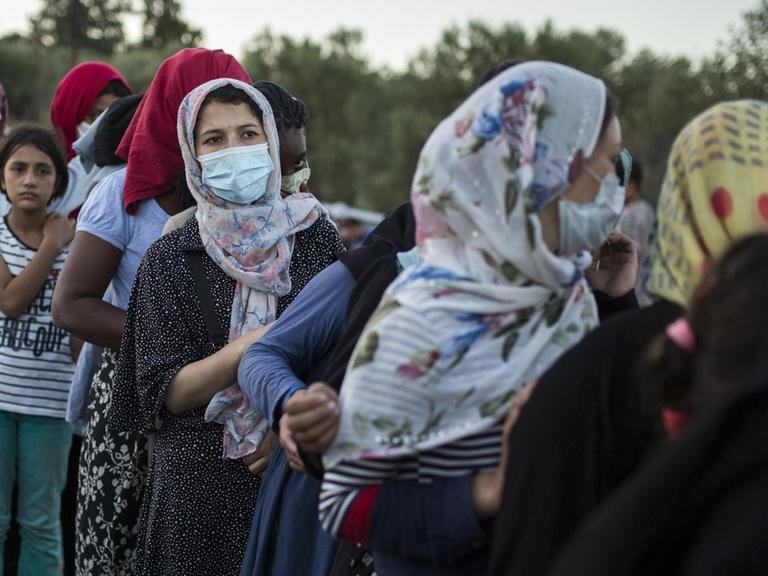 10.09.2020, Griechenland, Moria: Frauen stehen an, um Essen zu erhalten in der Nähe des ausgebrannten Flüchtlingslagers Moria. Mehrere Brände haben das Lager fast vollständig zerstört.