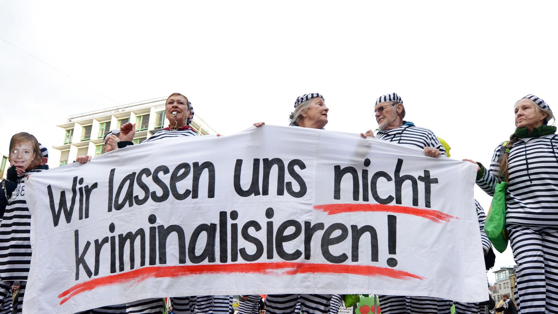 Teilnehmer der Montagsdemonstration gegen das umstrittene Bahnprojekt Stuttgart 21 laufen am 03.03.2014 bei einem "politischen Rosenmontagsumzug" als Gefangene verkleidet durch Landeshauptstadt Stuttgart (Baden-Württemberg). Sie haben dabei ein Transparent mit der Aufschrift: "Wir lassen uns nicht kriminalisieren". Die Gegner des Bahnprojekts Stuttgart 21 demonstrieren seit mehreren Jahr bei einer Montagsdemo gegen das Bauvorhaben. Teilnehmer der Montagsdemonstration gegen das umstrittene Bahnprojekt Stuttgart 21 laufen am 03.03.2014 bei einem "politischen Rosenmontagsumzug" als Gefangene verkleidet durch Landeshauptstadt Stuttgart (Baden-Württemberg). Sie haben dabei ein Transparent mit der Aufschrift: "Wir lassen uns nicht kriminalisieren". Die Gegner des Bahnprojekts Stuttgart 21 demonstrieren seit mehreren Jahr bei einer Montagsdemo gegen das Bauvorhaben.