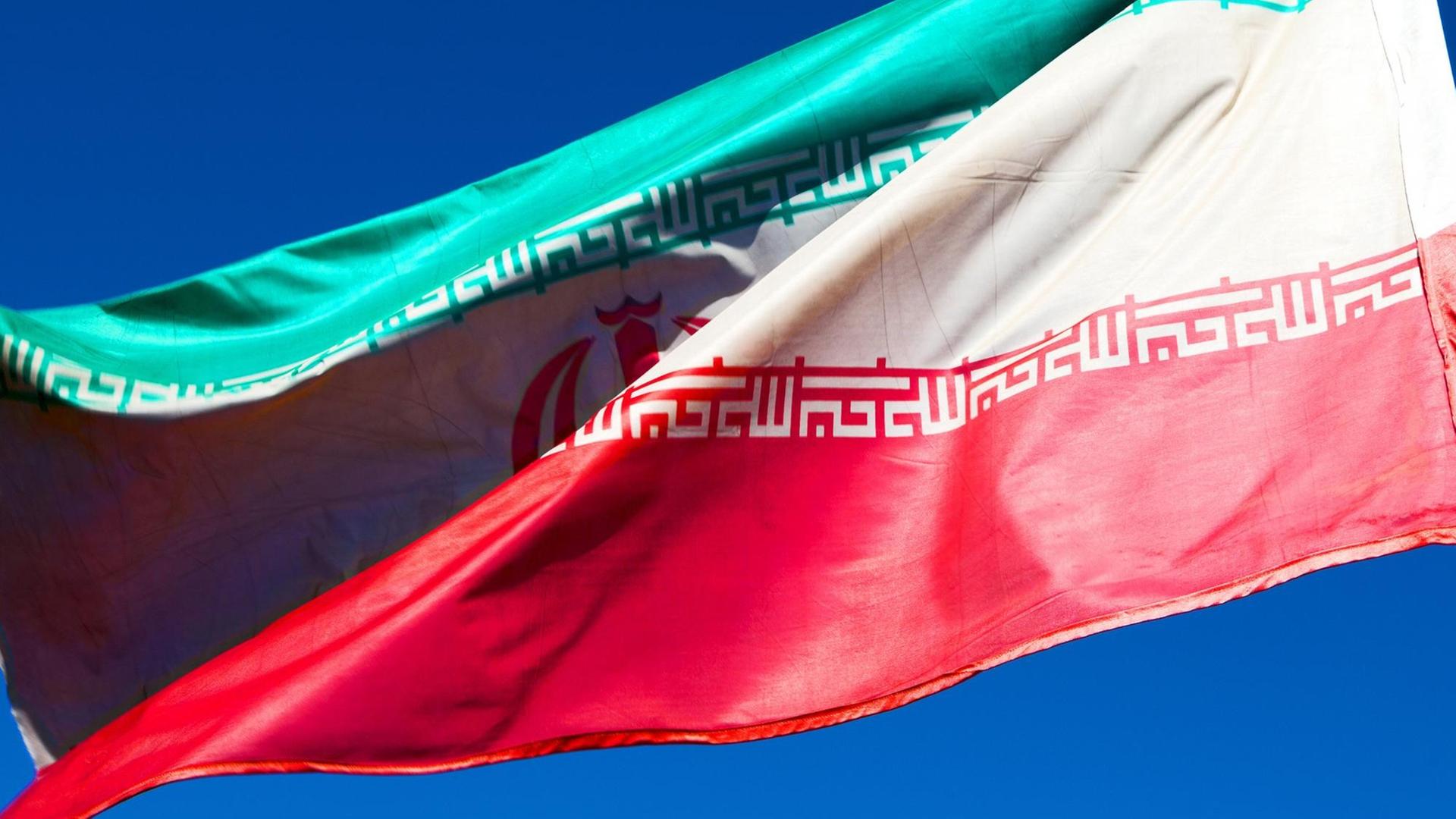 Iranische Flagge weht vor blauem Himmel Iranische Flagge weht vor blauem Himmel