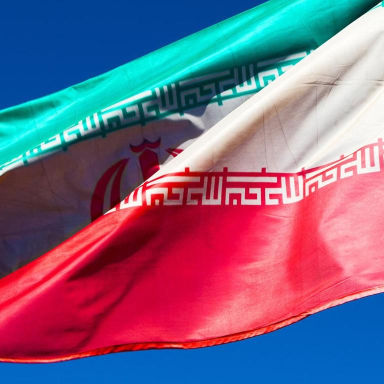 Iranische Flagge weht vor blauem Himmel